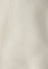 Tissu texturé dans une couleur beige clair avec un motif tissé subtil. Fini lisse avec une apparence douce. Matériau utilitaire adapté à l'ameublement.