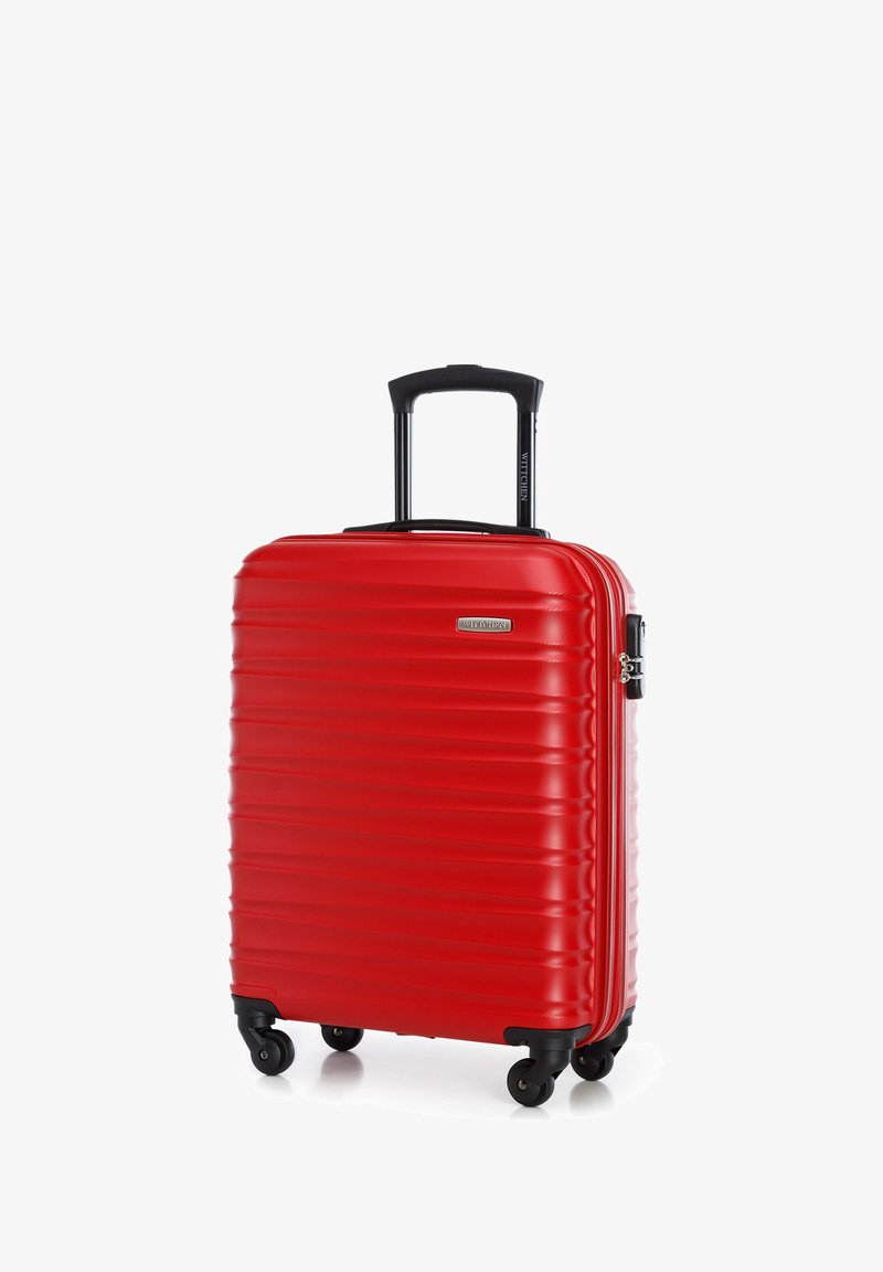Valise rigide rouge avec un design strié, poignée rétractable noire et quatre roues pour la mobilité. Comprend une fermeture éclair et un détail en métal avec logo.