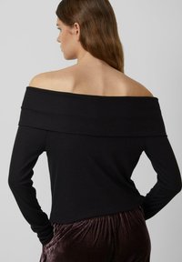 Schwarzes, geripptes Oberteil mit langen Ärmeln und schulterfreiem Schnitt, das einen gefalteten Kragen und einen figurbetonten Schnitt aufweist. Das Material wirkt weich und elastisch.