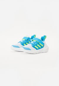 Baskets de sport bleu et blanc avec une tige en maille, présentant des accents vert fluo, une sangle velcro et un col rembourré pour le confort.