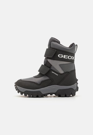 Stivale invernale impermeabile nero e grigio con suola robusta, cinturini in velcro e design in materiale tessile e sintetico. Il marchio Geox è evidente.
