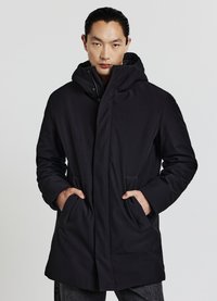 Parka impermeabile nera con collo alto, cappuccio fisso, due tasche frontali e texture liscia. Presenta una chiusura con zip e bottoni a pressione.