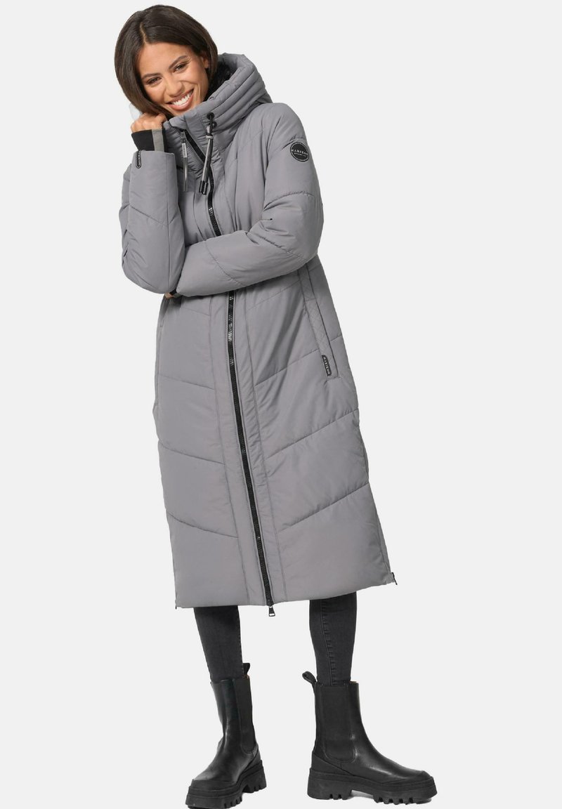 Grey padded long coat with a high collar and front zipper. Features angled stitching and side pockets. Worn with black chunky boots.