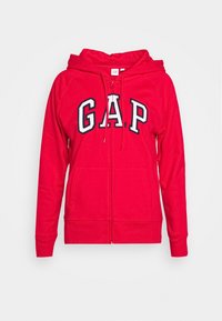 Sudadera con cremallera roja hecha de tejido suave, con un gran logo blanco y azul marino "G.A.P." en la parte frontal, dos bolsillos frontales y capucha con cordón.