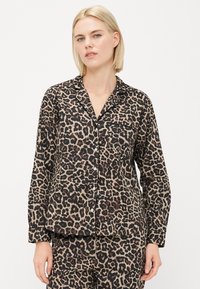 Pysjamasett med leopardmønster i brunt og svart, som har en skjorte med knapper, brystlomme og lange ermer, vist sammen med matchende bukser.