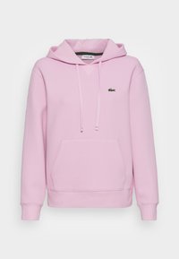 Sudadera con capucha rosa que presenta un bolsillo tipo canguro, puños y dobladillo acanalados, y un pequeño logo de cocodrilo verde en el pecho.