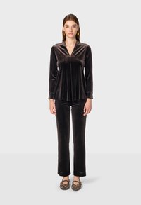 Čierne zamatové tričko s dlhým rukávom a výstrihom do V, doplnené o zladené nohavice. Oblečenie má hladkú textúru a uvoľnený strih.