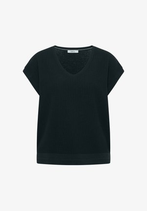 Femme aux cheveux bruns et raides portant un haut en maille texturée noire à manches courtes, vue de dos sur un fond uni.