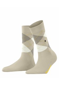 Beige argyle-sokker med grå og hvide diamantmønstre, gule syninger som accent og ribbede manchetter, hvor der er et logo nær tåen.