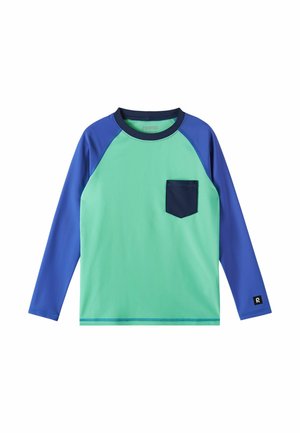 Koszula z długim rękawem, z miętowo-zielonym przodem, niebieskimi rękawami i kołnierzem, granatową kieszenią na piersi i małym czarnym logo na lewej mankiecie rękawa.