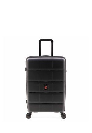 Valigia rigida nera con manico retrattile e quattro ruote girevoli, in piedi su uno sfondo bianco.