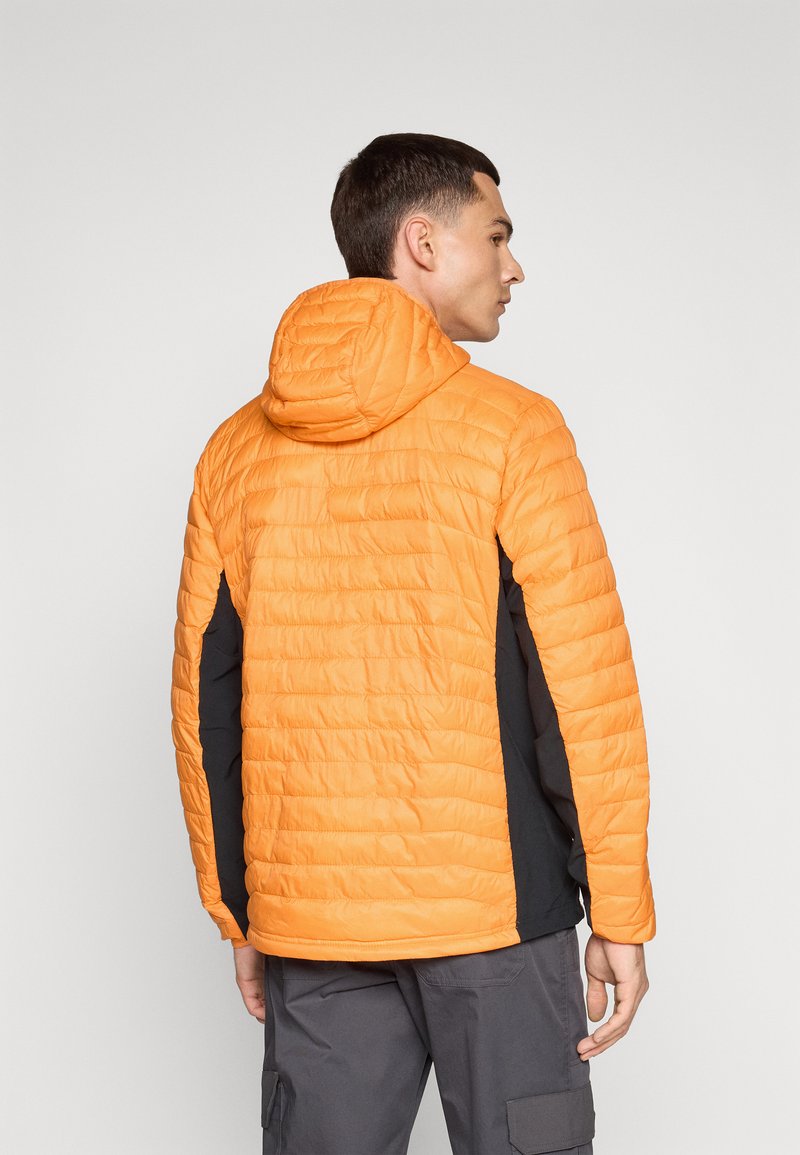 Doudoune avec un design matelassé orange et un panneau latéral noir. Comprend une capuche et un tissu léger pour l'isolation.