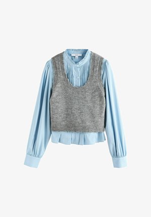 Gilet en tricot gris superposé sur une blouse plissée bleu clair à fermeture bouton et manches longues, avec des poignets froncés et un col volanté.
