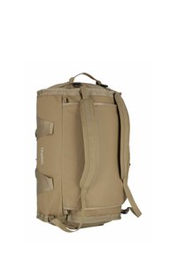 Bolso de deporte color tan con forma cilíndrica, que cuenta con dos correas laterales, un bolsillo frontal y costuras reforzadas. Material duradero y diseño minimalista.