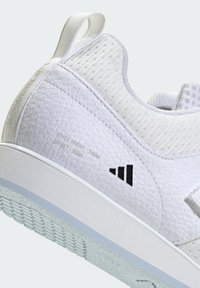 Biały but sportowy z teksturowaną cholewką, siateczkowymi częściami, wyściełanym kołnierzem i czarnym logo. Posiada gumową podeszwę z sześciokątnym wzorem.