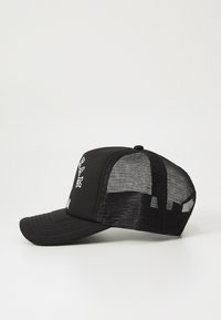 Svart caps med nettbakside og solid front. Har brodert tekst på fronten. Buet skjerm med sømdetaljer.