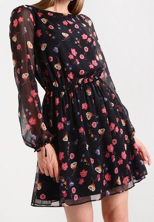 Zwarte doorschijnende jurk met lange mouwen, bedrukt met bloemen in roze, paars en beige, een getailleerde taille en een licht uitlopende rok.