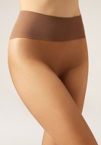 Collants taille haute nude sans couture avec une finition mate, présentant une texture douce et une taille lisse et flexible. Design élégant et ajusté.