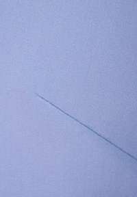 Jasnoniebieska tkanina o gładkiej fakturze, z ukośnym detalem szwu i delikatnym, tkanym wzorem.