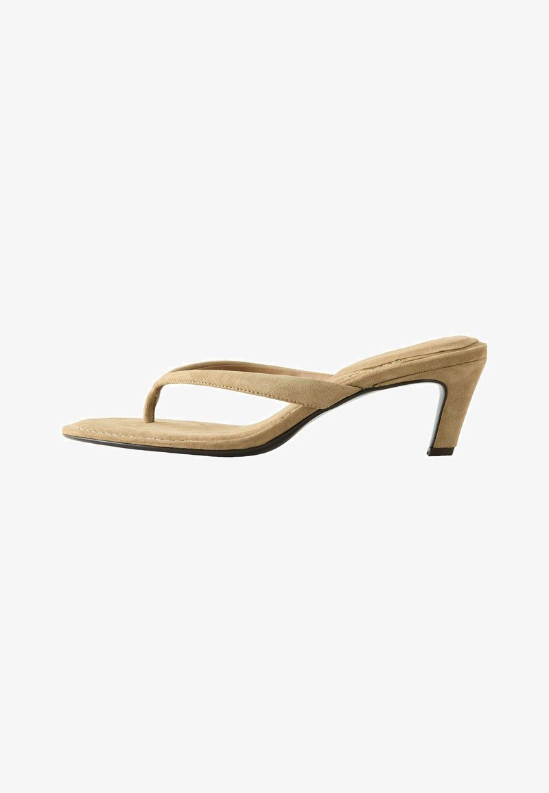 Sandale à talon pour femme en daim beige avec bride en tongs et talon bas effilé sur fond blanc.