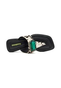 Sandales noires avec une sangle blanche éclaboussée et un large faux gemme vert. La semelle est plate et faite d'un matériau noir texturé.