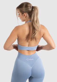 Lichtblauwe sportoutfit met een halter-style sportbeha en hoge taille leggings, met een geribbelde textuur en subtiele logo-accenten.
