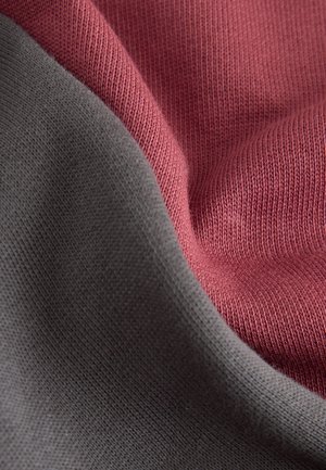 Knit fabric featuring a maroon and dark gray color scheme. Smooth texture with visible ribbing and subtle folds creating soft shadows.