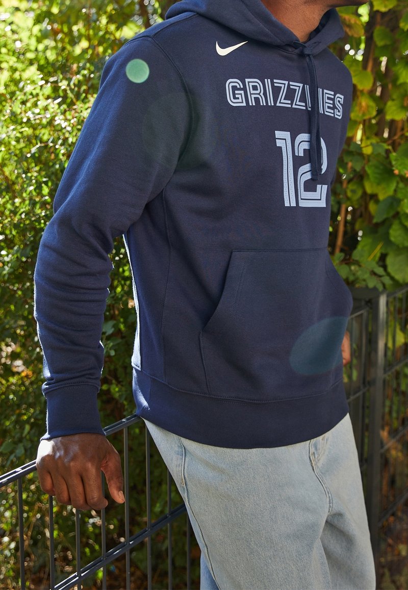Felpa Nike blu navy con tasca frontale, testo "GRIZZLIES" e numero "12" in azzurro chiaro. Materiale morbido simile al pile con cappuccio regolabile.
