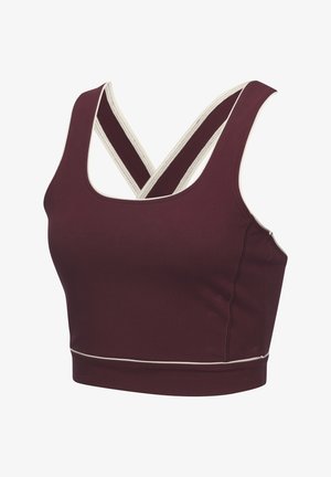 Top sportivo corto color mogano con scollatura a barca, caratterizzato da spalline incrociate e bordi bianchi. Realizzato in tessuto elasticizzato e liscio per il massimo comfort.