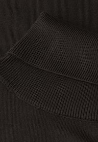Schwarzer geripptes Material mit einer Nahaufnahme eines Folds, die die Textur und das Strickmuster zeigt. Das Material wirkt weich und flexibel.