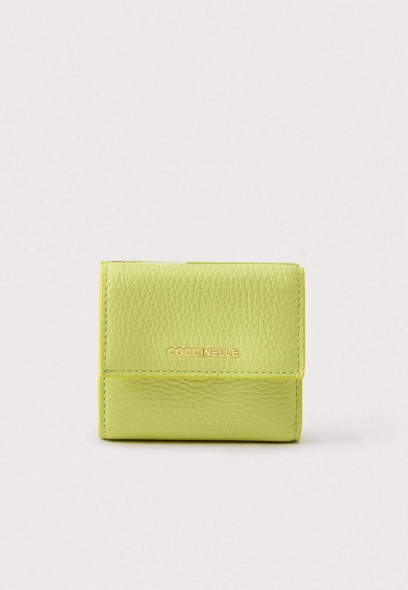 Lysegrønn lommebok i skinn med en strukturert overflate, utstyrt med klaffelås og gullfarget "Coccinelle"-merke på forsiden. Kompakt design.