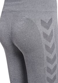 Close-up van grijs gestructureerde leggings met een geribde tailleband en een chevronpatroon langs de buitenkant van de dij.