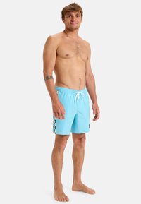 Svetlomodré plavky s vzorovanou kockovanou bočnou stranou. Vyrobené z mäkkého, rýchloschnúceho materiálu, s elastickým pásom a šnúrkou na stiahnutie.