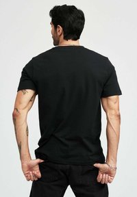 Svart bomull t-shirt med korta ärmar, klassisk rund hals, figurnära design och en mjuk textur, tillsammans med svarta byxor.