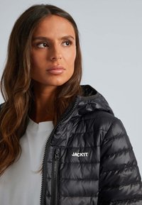 Zwarte pufferjack met een ritssluiting aan de voorkant, geb quiltde textuur en capuchon. Voorzien van het witte logo "JACK1T" op het linkerborstgedeelte.