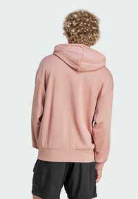 Felpa rosa chiaro con un ampio cappuccio e polsini a coste. Realizzata in tessuto morbido, ha una vestibilità comoda e una tasca a marsupio sul davanti.