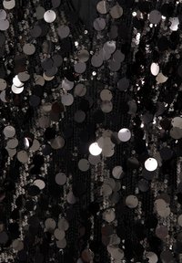 Schwarzer Paillettenstoff mit einer dichten Anordnung runder, reflektierender Pailletten in verschiedenen Farbtönen, der eine strukturierte, schimmernde Oberfläche erzeugt.