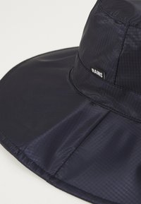 Cappello a secchiello impermeabile di colore blu navy, realizzato in tessuto morbido, con un'ampia visiera e un piccolo etichetta nera con la scritta "RAINS."