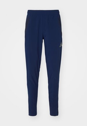 Navy athletic pants with elastic waistband, tapered fit, and side zipper pockets. Features subtle black accents and smooth texture.