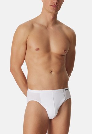 Weiße Baumwollslips mit glatter Textur und elastischem Bund. Die Vorderseite verfügt über einen unterstützenden Beutel und ein kleines Markenschild am Bund.