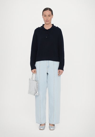 Marinblå stickad tröja med huva och knappdetalj, ljusblå vida jeans, silverfärgade metalliska ballerinas och en liten silverhandväska.