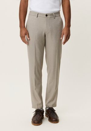 Pantalon gris clair avec une coupe ajustée, doté d'un devant plat, de passants pour ceinture et d'une fermeture à bouton unique. Porté avec des chaussures marron à lacets.