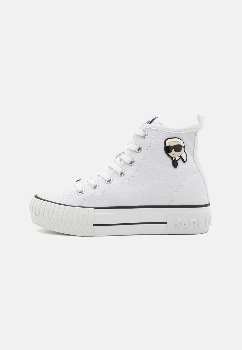 Kõrge valge kanvasest sneakers, millel on tekstureeritud kummist tald, mustad triibud ja külgedel koomiksitegelase märk. Lihtsad õmblusdetailid.