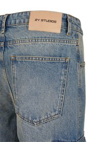 Jeans din denim albastru cu un eticheta din piele cu inscripția "2Y STUDIOS". Design standard pentru buzunarul din spate, cu cusături întărite și textură uzată.