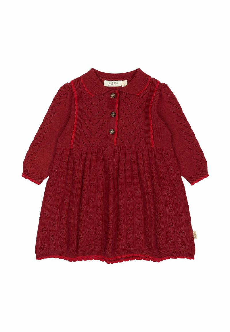 Punane kudum dress krae, kolme nupuga esikülg ja pikad varrukad. Omab teemantmotiive ja lainelisi ääriseid hemmi ja mansettide ääres.