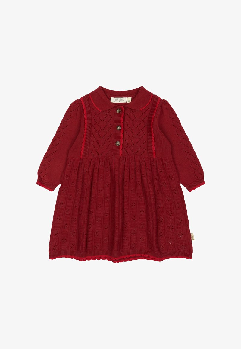 Punane kudum dress krae, kolme nupuga esikülg ja pikad varrukad. Omab teemantmotiive ja lainelisi ääriseid hemmi ja mansettide ääres.