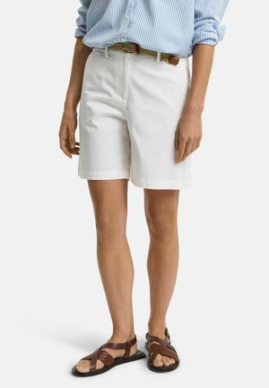 Shorts en coton blancs avec une coupe droite, taille mi-haute, et poches latérales, associés à des sandales à lanières marron. Chemise à rayures bleues rentrée.