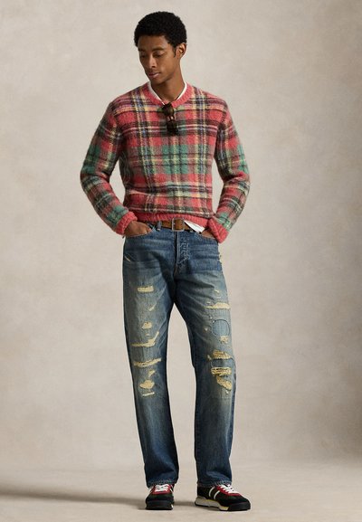 Flerfärgad rutmönstrad tröja i nyanser av rosa, grönt och gult. Bärs med slitna blå jeans och svarta sneakers, vilket ger en avslappnad känsla.