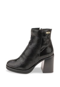 Botín negro hasta el tobillo con un acabado texturizado similar a la piel de serpiente, un tacón grueso y un cierre de cremallera en el lateral. Punta lisa y silueta elegante.