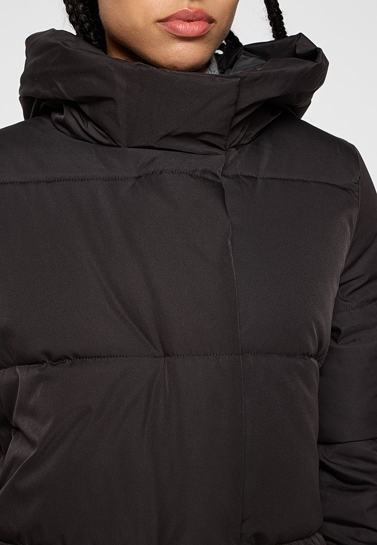 Schwarze Pufferjacke mit hohem Kragen, horizontalen Nähten und glatter Textur. Sie zeichnet sich durch eine enganliegende Passform und leichte Isolierung aus.